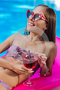 Happy woman sunbathing while lying on air mattress in the pool