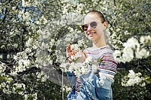 Happy woman in sunglasses on background of blossoming apple tree