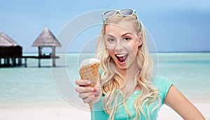 Happy woman in sunglasses with ice cream on beach