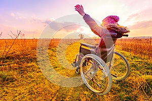 Happy woman at sunset. A young girl in a wheelchair