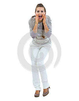 Happy woman in sweater shouting through megaphone shaped hands
