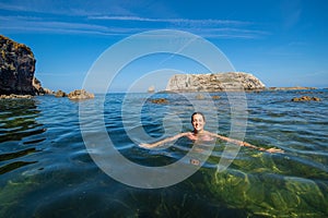 Happy woman swimming in the sea of an idyllic beach