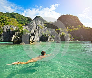 Happy woman swims in the crystal clear water near of islands