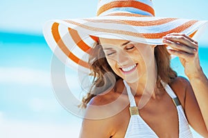 happy woman in swimsuit and beach hat at seaside