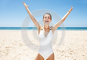 Happy woman in swimsuit at sandy beach on sunny day rejoicing