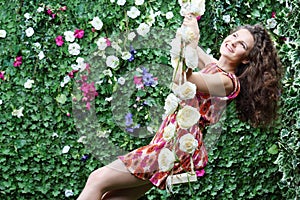 Happy woman swings on swing overgrown with flowers