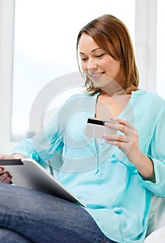 Happy woman with tablet pc and credit card at home