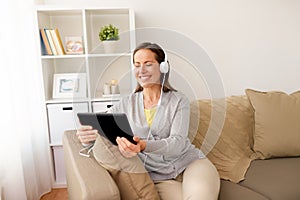 Happy woman with tablet pc and headphones at home