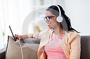 Happy woman with tablet pc and headphones at home