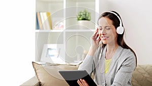 Happy woman with tablet pc and headphones at home