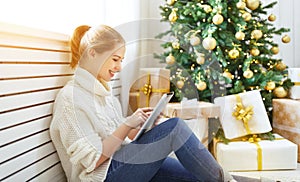 Happy woman with tablet pc at morning near Christmas tree