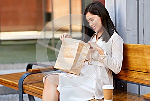 Happy woman with takeaway coffee and lunch in city