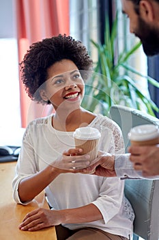 Happy woman taking coffee from man in office