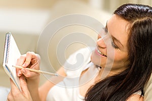 Happy woman taking notes into notepad