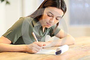Happy woman taking notes on paper notebook on table