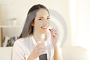 Happy woman taking painkiller capsule at home photo