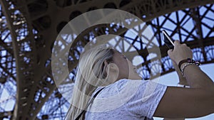 Happy woman taking panoramic picture under Eiffel Tower