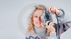 Cute woman taking a photo with a camera on a white background