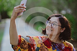 Happy woman taking a selfie with her mobile phone in a blooming park