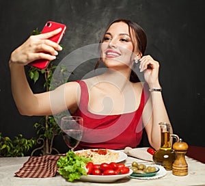 Happy woman taking selfie photo and eating italian pasta in restaurant