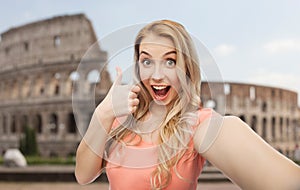 Happy woman taking selfie and showing thumbs up