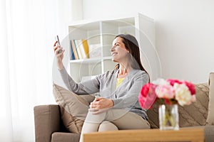 Happy woman taking selfie smartphone at home
