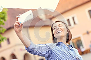 Happy woman taking selfie in a town