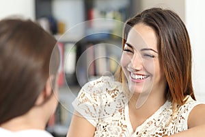 Happy woman talking and laughing with a friend at home