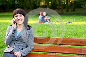 Happy woman talking on mobile phone in park