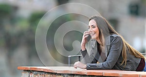 Happy woman talking on phone in a balcony