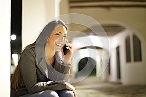 Happy woman talking on phone in the night in the street