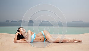 Happy woman tanning in bikini over swimming pool