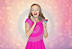 Happy woman or teen girl eating birthday cupcake