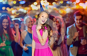 Happy woman or teen in party cap at night club