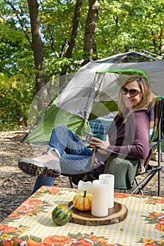 Happy woman tent camping in fall holding a mug of coffee in morn