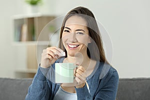 Happy woman throwing sugar into mug looking at you
