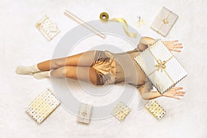 Happy woman throwing up a present box lying among wrapping christmas gifts for family on fluffy snow-white carpet. Top view.