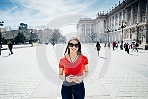 Happy woman tourist in front of Cathedral Santa Maria la Real de La Almudena in Madrid,Spain.Tourist using vacation sim card