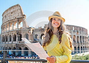 Happy woman tourist looking up from map at Rome Colosseum