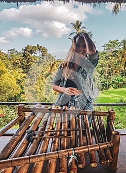 Happy woman tourist with traditional bamboo percussion intrument in Bali photo