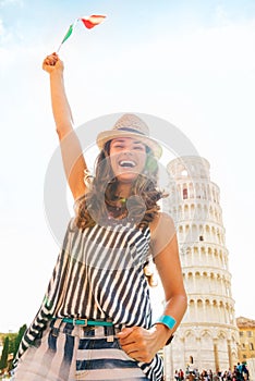 Happy woman tourist waving flag at Leaning Tower of Pisa