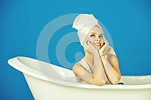 Happy woman with towel turban sitting in white bathtub