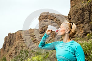 Happy woman trail runner drinking water in mountains