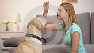 Happy woman training dog and giving food, teaching pet to bark, discipline