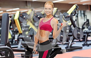 Happy woman training with light dumbbells in gym
