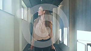 Happy woman with travel suitcase walking at hotel corridor