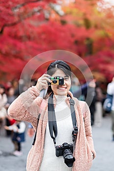 Happy woman traveler taking photo colorful leaves in the garden, Asian tourist visit in Kyoto city, Japan and enjoying with