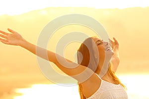 Happy woman trstching arms breathing fresh air at sunset