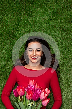 Happy woman with tulips lying on meadow