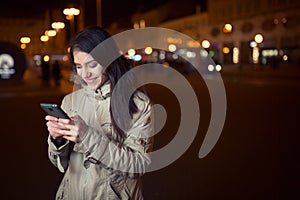 Happy woman typing text message on a smart phone on a city street while waiting.Euphoric woman watching her smart phone